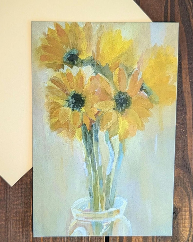 Puede incluir: Una pintura de acuarela de girasoles en un jarr&oacute;n de cristal. Los girasoles son amarillos con centros oscuros, y el jarr&oacute;n es transparente. El fondo es de un color suave y apagado. La pintura est&aacute; en una tarjeta de felicitaci&oacute;n.