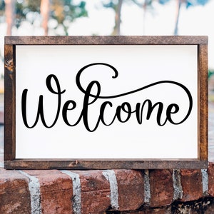May include: A wooden framed sign with the word "Welcome" written in a decorative script font.