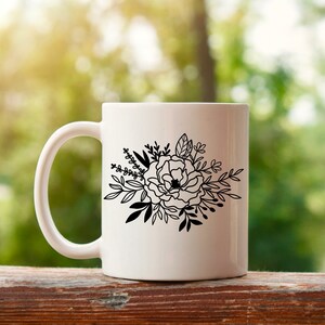 以下が含まれることがあります： 白いセラミック製のマグカップに、黒い線で描かれた花束が描かれています。花束には、大きな花びらがたくさんついた大きな花と、小さな花や葉が描かれています。