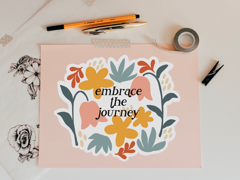 May include: A pink background with a white sticker featuring a floral design and the text "embrace the journey".