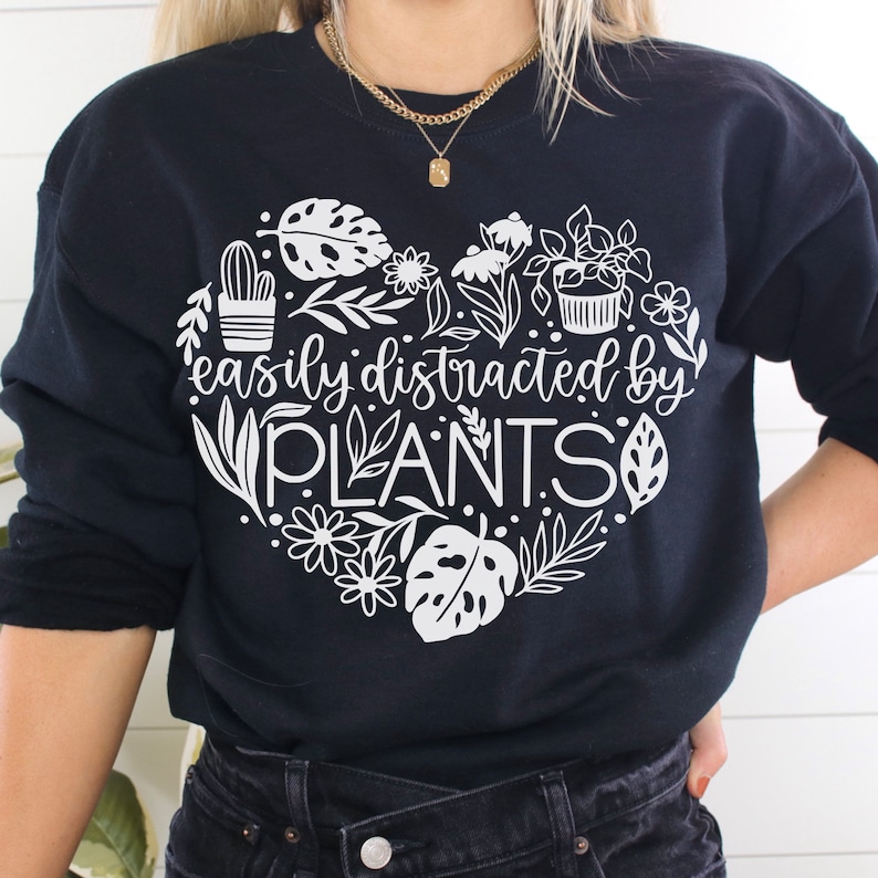 May include: Black sweatshirt with a white heart design featuring plants and the text "easily distracted by PLANTS".