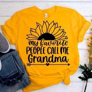 May include: Yellow t-shirt with a black sunflower graphic and the text "my favorite people call me grandma" with a heart and arrows.