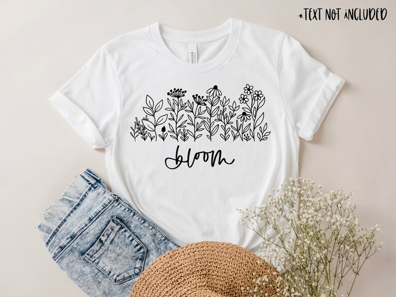 May include: White t-shirt with a black line drawing of flowers and the word "bloom" printed on the front.