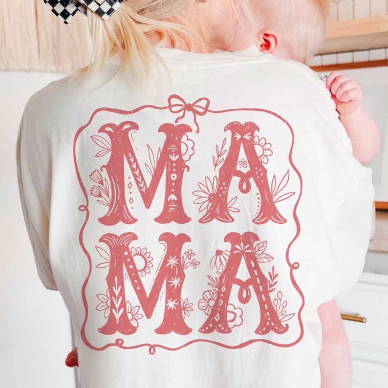 May include: A white t-shirt with a pink floral design that says "MAMA" on the back.