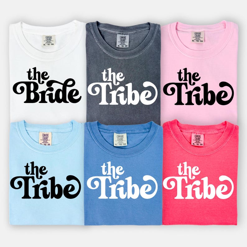 May include: Six t-shirts in different colors with the text "the Bride" and "the Tribe" in a retro font. The shirts are all the same style and size.
