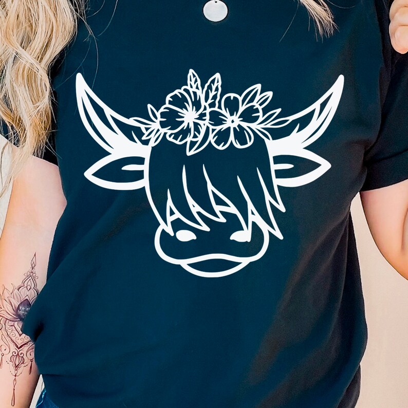 May include: Black t-shirt with a white outline of a Highland cow wearing a flower crown.