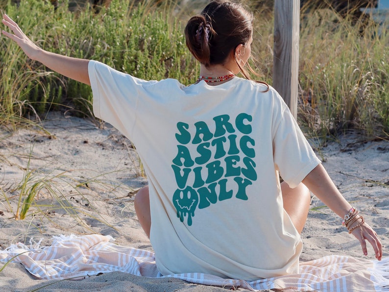 May include: A white t-shirt with a green graphic that says "SARCASTIC VIBES ONLY" with a dripping smiley face.