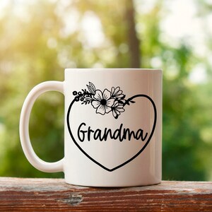 May include: White ceramic mug with a black heart design that says "Grandma" and a floral design above the heart.
