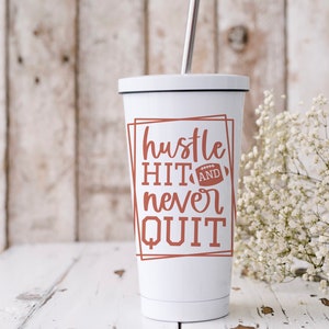 May include: White tumbler with a brown graphic that says "hustle hit and never quit" with a football graphic. The tumbler has a black lid and a silver straw.