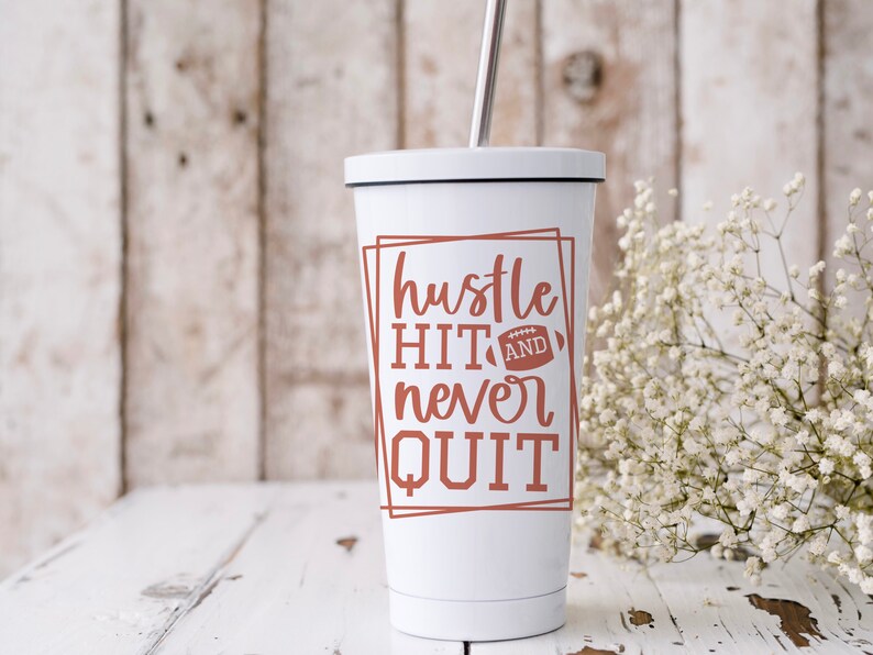 May include: White tumbler with a brown graphic that says "hustle hit and never quit" with a football graphic. The tumbler has a black lid and a silver straw.