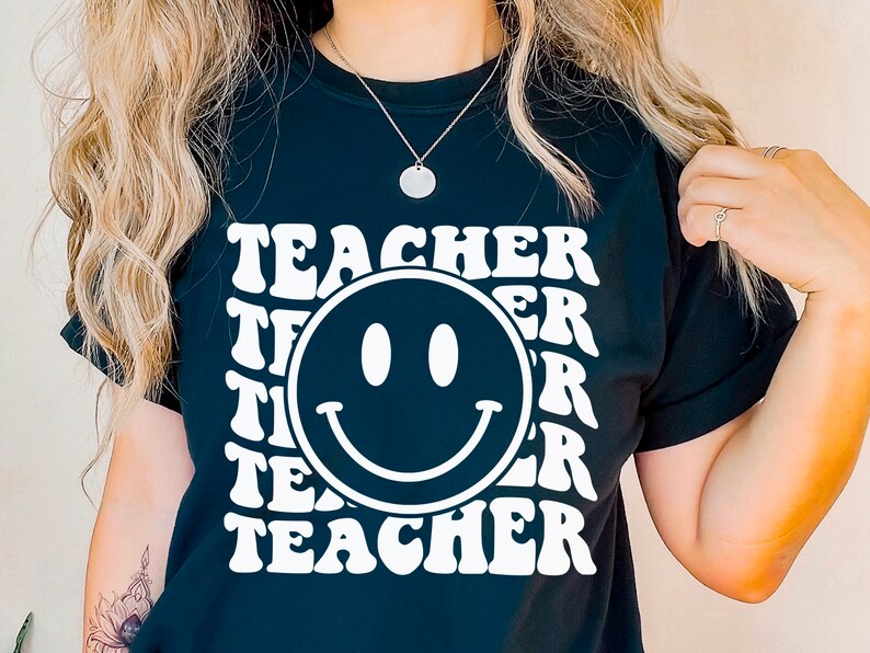 May include: Black t-shirt with a white smiley face and the word "TEACHER" repeated in a retro font.