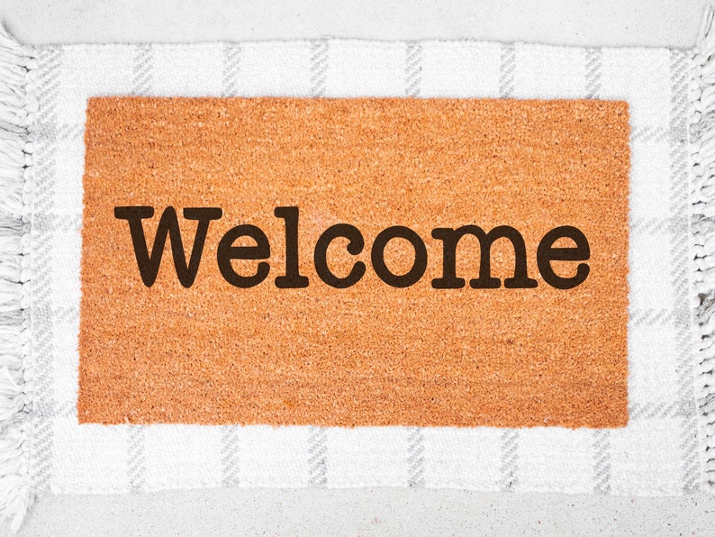 May include: A brown coir doormat with the word "Welcome" in black lettering.