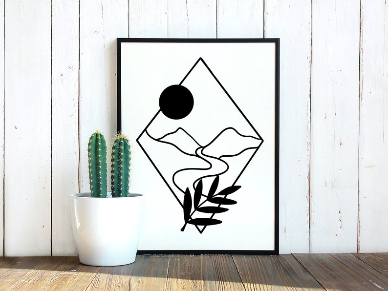 May include: Black framed art print with a minimalist landscape design. The print features mountains, a river, and a sun. A black and white botanical illustration is in the lower right corner. Two cacti in a white pot are to the left.