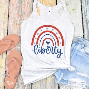 K&ouml;nnte beinhalten: Ein graues Tanktop mit einem rot-wei&szlig;-blauen Regenbogenmuster und dem Wort "liberty" in blauer Schrift. Der Regenbogen hat wei&szlig;e Sterne und ein kleines blaues Herz in der Mitte.