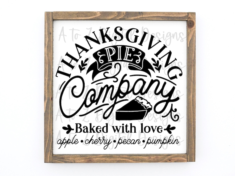 May include: A brown wooden framed sign with a white background and black text that reads "Thanksgiving Pie Company Baked with love apple. cherry. pecan. pumpkin". The sign features a stylised pie with a crust and a decorative banner that reads "Pie".