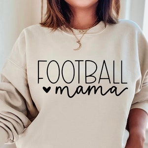 May include: A cream-colored sweatshirt with the text "FOOTBALL mama" in black lettering. A small heart is in front of the word "mama".