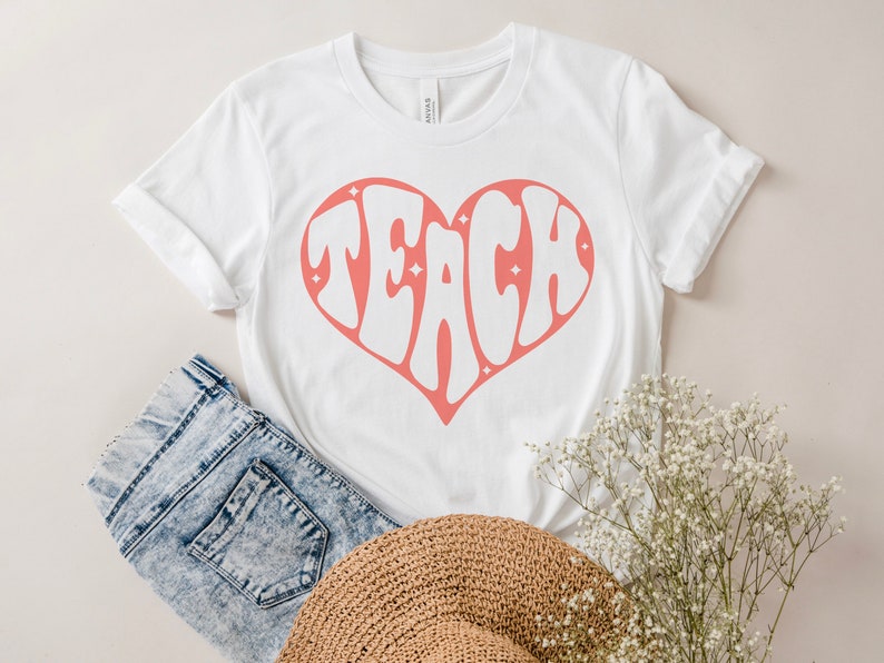 May include: White t-shirt with a pink heart design that says "TEACH" inside the heart.