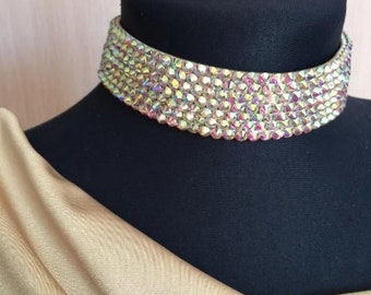 Può includere: Un girocollo scintillante e iridescente fatto di piccoli strass. Il girocollo è su un busto di manichino nero.