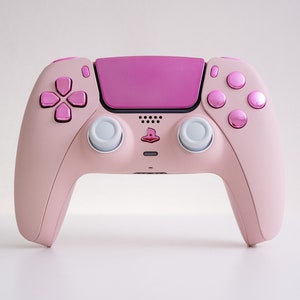 Könnte beinhalten: Ein rosa PlayStation 5 DualSense-Controller mit rosa Knöpfen und einer rosa Frontplatte.