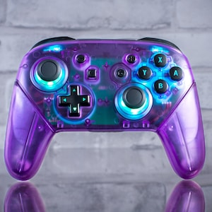 May include: A white ceramic mug with a black handle and the text "But First, Coffee" in a handwritten style. The mug is on a white surface. The mug is approximately 10 cm tall.