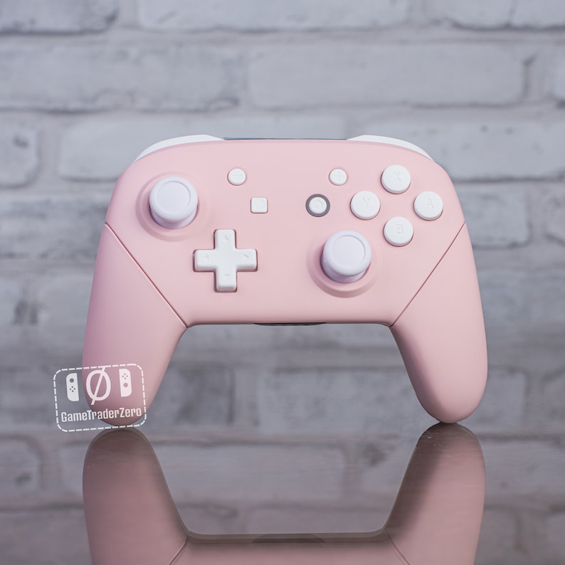 Pu&ograve; includere: Un controller Nintendo Switch rosa con pulsanti e joystick bianchi. Il controller ha una superficie testurizzata ed &egrave; progettato per il gioco.
