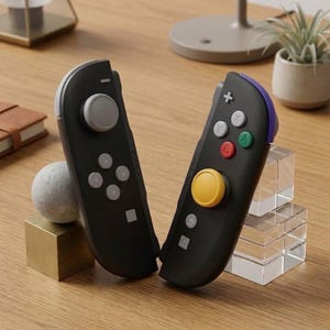 May include: A pair of black gaming controllers featuring a gray analog stick and directional buttons on the left unit, and a yellow analog stick with red, green, and gray action buttons on the right unit, accented with a purple top edge.