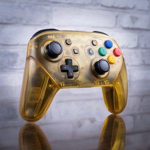 May include: A translucent yellow Nintendo Switch controller with black buttons and colored buttons labeled X, Y, and B.