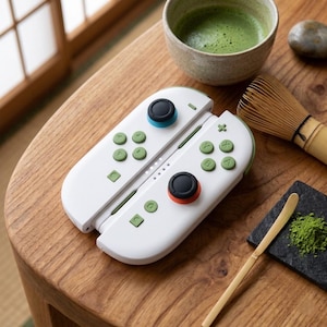 May include: A white video game controller with green buttons, a blue joystick cap, and an orange joystick cap. The controller features a directional pad, action buttons labelled A, B, X, and Y, and additional function buttons, all arranged on a sleek, rounded white housing.