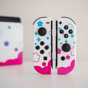 Pode incluir: Um par de controladores Nintendo Switch Joy-Con brancos com um padr&atilde;o de estrelas e nuvens rosa, azul e branco. Os controladores t&ecirc;m os bot&otilde;es padr&atilde;o: A, B, X, Y, mais, menos e home.