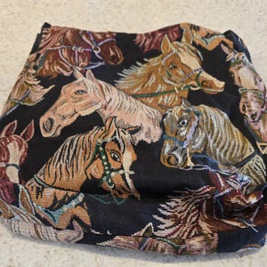 May include: A black fabric textile featuring a repeating woven pattern of horse heads in various shades of brown, tan, and cream. The horses are depicted with detailed manes and bridles, creating a dense, multi-colored equestrian design.