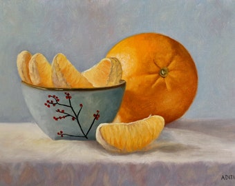 Puede incluir: Un tazón azul con bayas rojas pintadas en él, lleno de segmentos de naranja, se sienta sobre un mantel blanco junto a una naranja entera.