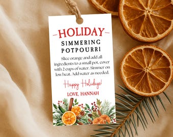 May include: A white tag with the text "HOLIDAY SIMMERING POTPOURRI" and instructions for use. The tag is tied with twine and decorated with illustrations of oranges, cinnamon sticks, and greenery. Dried orange slices and a sprig of pine are also visible.