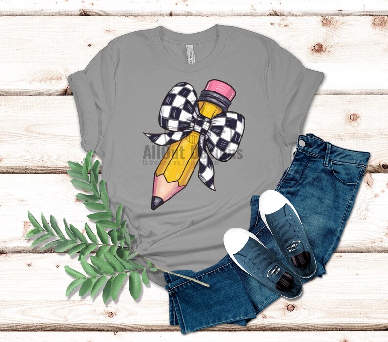 May include: A grey t-shirt featuring a yellow pencil with a black and white chequered bow.