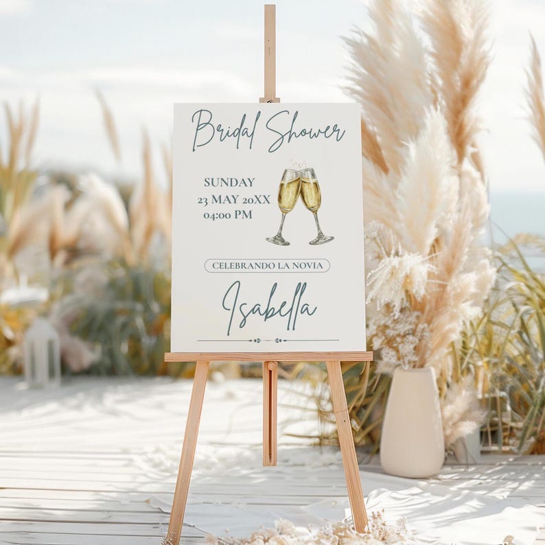 K&ouml;nnte beinhalten: Eine Holzstaffelei zeigt ein Schild f&uuml;r eine Brautparty. Auf dem Schild steht "Bridal Shower" mit Datum und Uhrzeit sowie dem Namen "Isabella". Zwei Champagnergl&auml;ser sind auf dem Schild abgebildet.