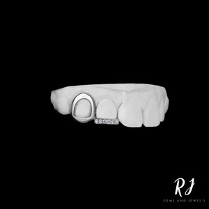 May include: A silver tooth grill with a diamond-encrusted bar. The grill is designed to fit over two teeth and has a unique, open-circle design.