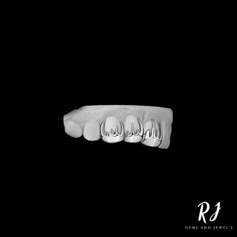 May include: A close-up of a silver grill with a pointed design. The grill is set on a white mold.
