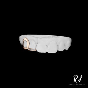 May include: A gold tooth grill with a diamond-encrusted bar. The grill is designed to fit over a single tooth.