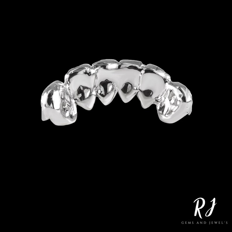 May include: Silver grill with five teeth, each shaped like a heart. The grill is designed to fit over the front teeth.