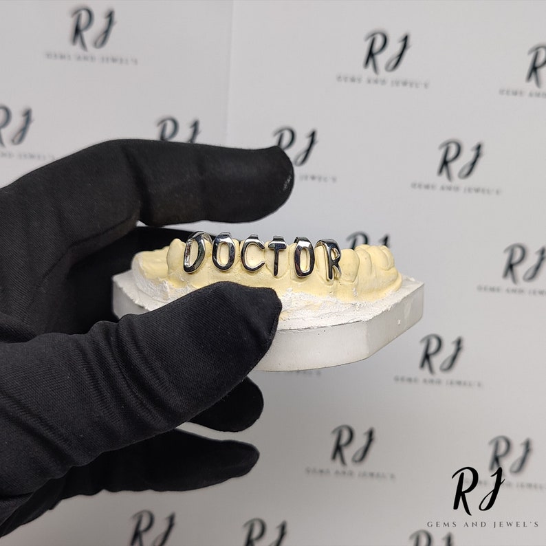 May include: A close-up of a gold grill with the word "DOCTOR" spelled out in individual letters.