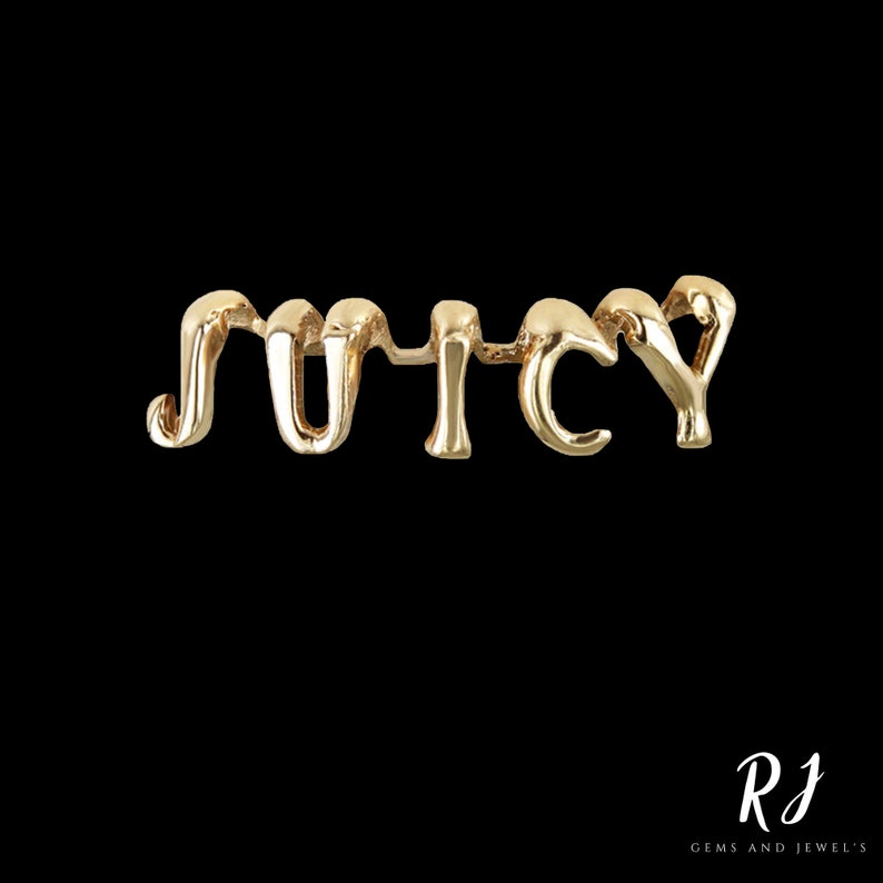 May include: Gold-toned metal charm with the word "JUICY" spelled out in a stylized, cursive font.