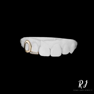 May include: Gold tooth grill with a diamond-encrusted bar. The grill is designed to fit over a front tooth.