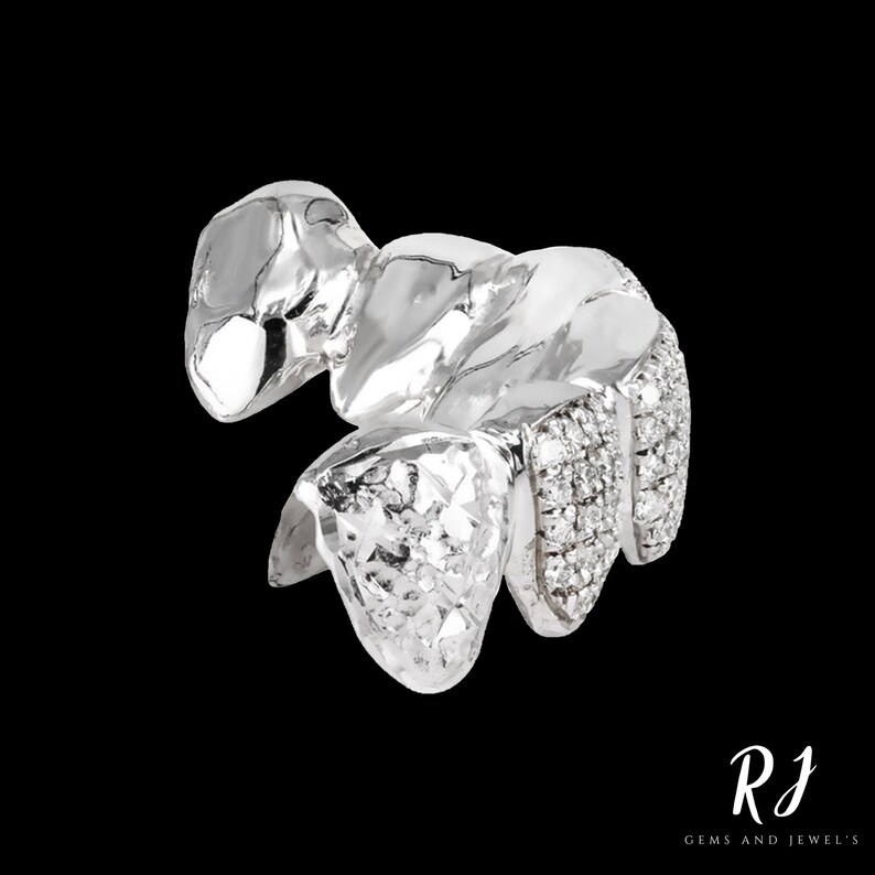 May include: Silver grill with diamond accents. The grill is made of metal and has a textured surface. The diamonds are set in the metal and are arranged in a pattern.