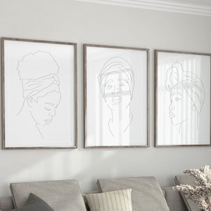 May include: Three framed line drawings of women with headscarves. The drawings are in black and white and are set against a white wall.