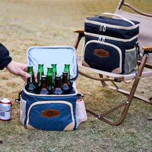 May include: Two blue and beige insulated cooler bags with zip closures. One bag is open and contains several bottles of beer. The bag has a personalised name tag that says "RDJ".