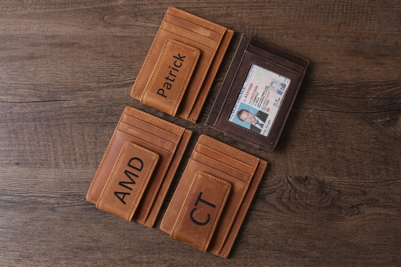 May include: Four brown leather wallets with money clips. The wallets have different names engraved on them: Patrick, AMD, CT, and one with a driver's license inside.