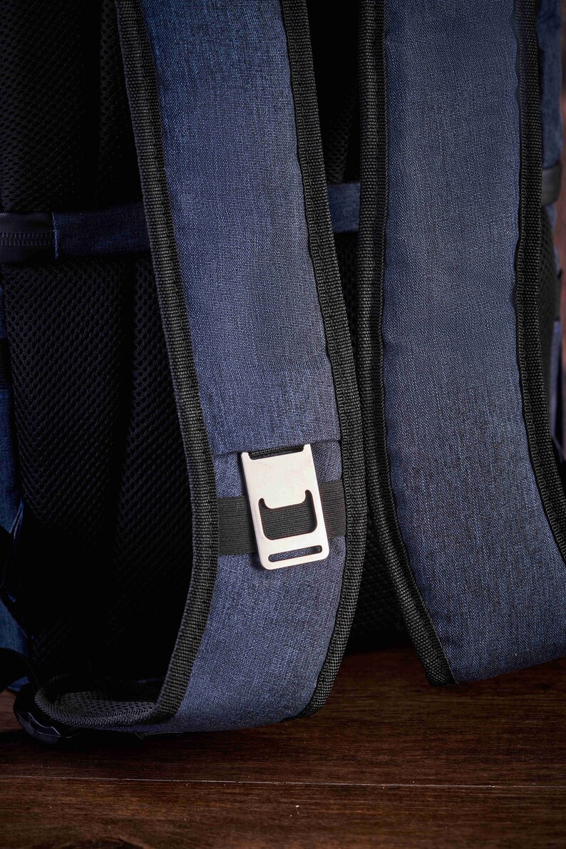 May include: A blue backpack with black straps and a silver buckle. The backpack is made of a textured fabric.