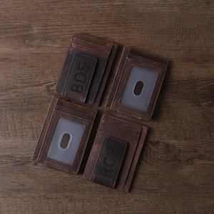 May include: Four brown leather wallets with a money clip and a clear ID window. The wallets are personalized with the initials BDS and RCH.