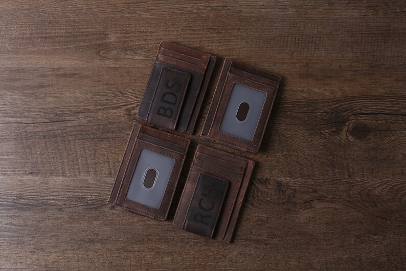May include: Four brown leather wallets with a money clip and a clear ID window. The wallets are personalized with the initials BDS and RCH.