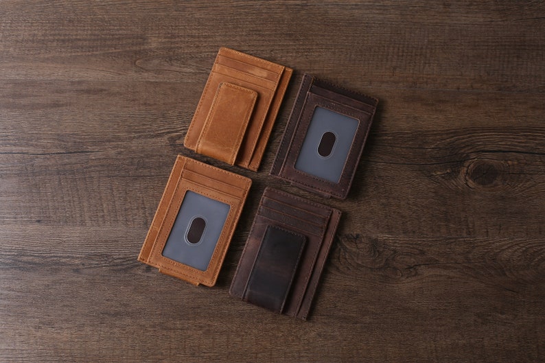 May include: Four leather wallets with a money clip. The wallets are brown, dark brown, and tan. The wallets have a single card slot and a money clip.