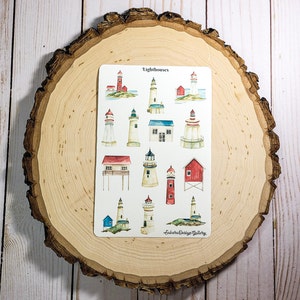 May include: A sticker sheet featuring watercolor illustrations of various lighthouses. The lighthouses are depicted in red, white, blue, and green, with some set on small islands. The text "Lighthouses" is at the top of the sheet, and the artist's name is at the bottom.